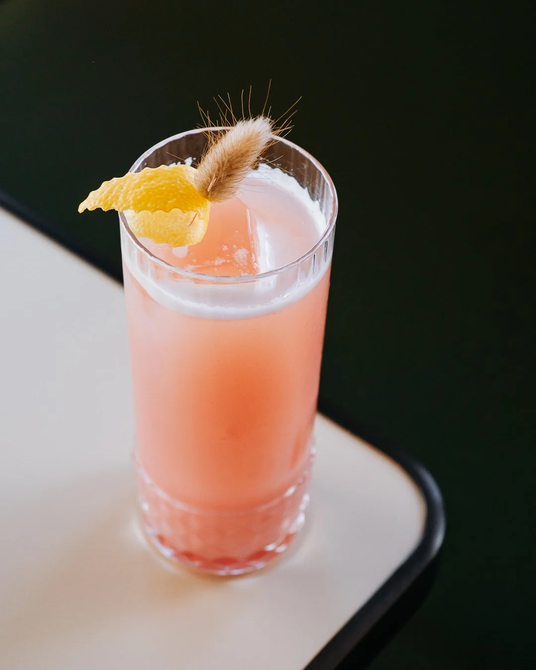 Plan rapproché sur un verre de cocktail et sa bouteille Lionel Osmin, lumière douce et ambiance chic