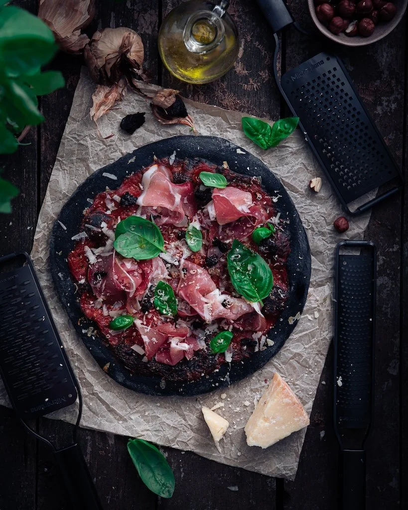 Photographie culinaire d'une pizza noire au charbon et ail noir pour la collaboration Microplane Black Sheep