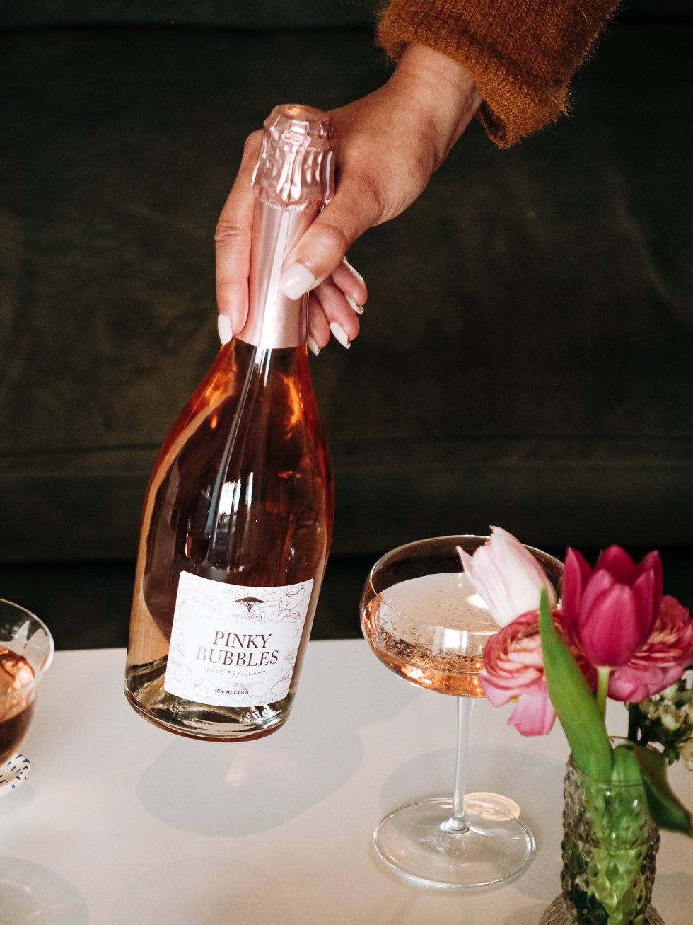Une mannequin main sert le pétillant rosé Pinky Bubbles dans une ambiance fraîche et fleurie dans le 64