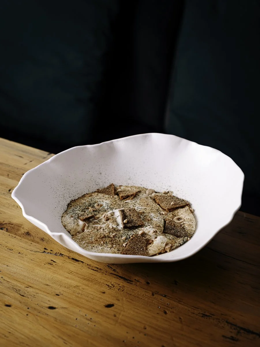Assiette creuse blanche avec un dressage texturé et noisettes, photographe culinaire