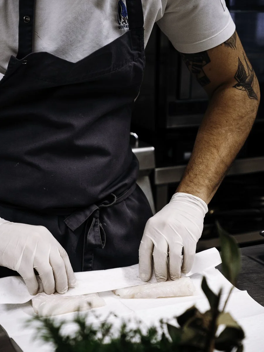 Mains du chef préparant un filet de poisson blanc lors d'un reportage métier à Pau