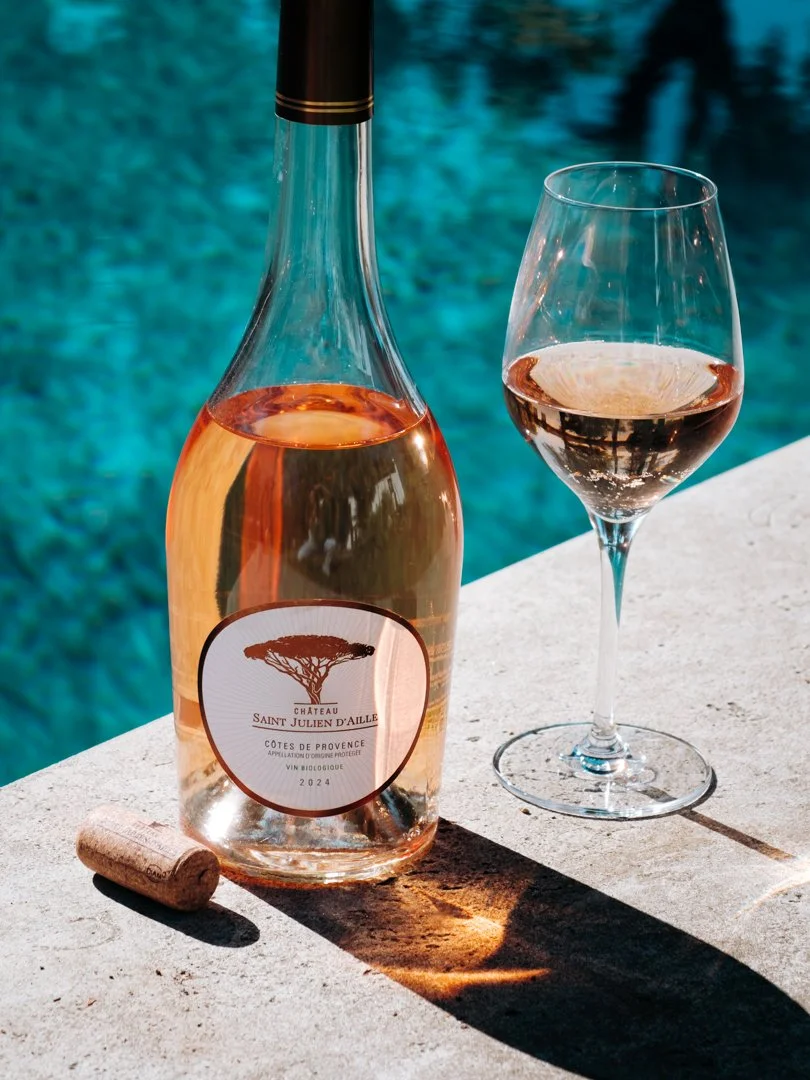 Bouteille de vin rosé Domaine et verre posés au bord d'une piscine ensoleillée au Pays Basque