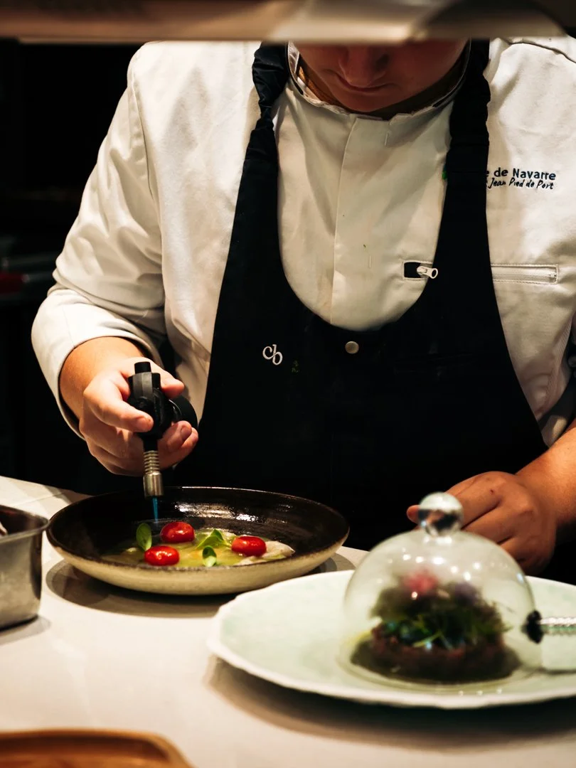 Utilisation d'un chalumeau de cuisine sur des tomates cerises lors d'un reportage culinaire