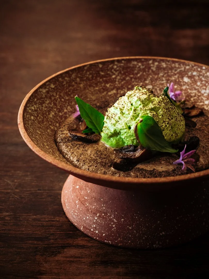 Entrée composé d'une mousse verte et de pousses de basilic sur une céramique texturée