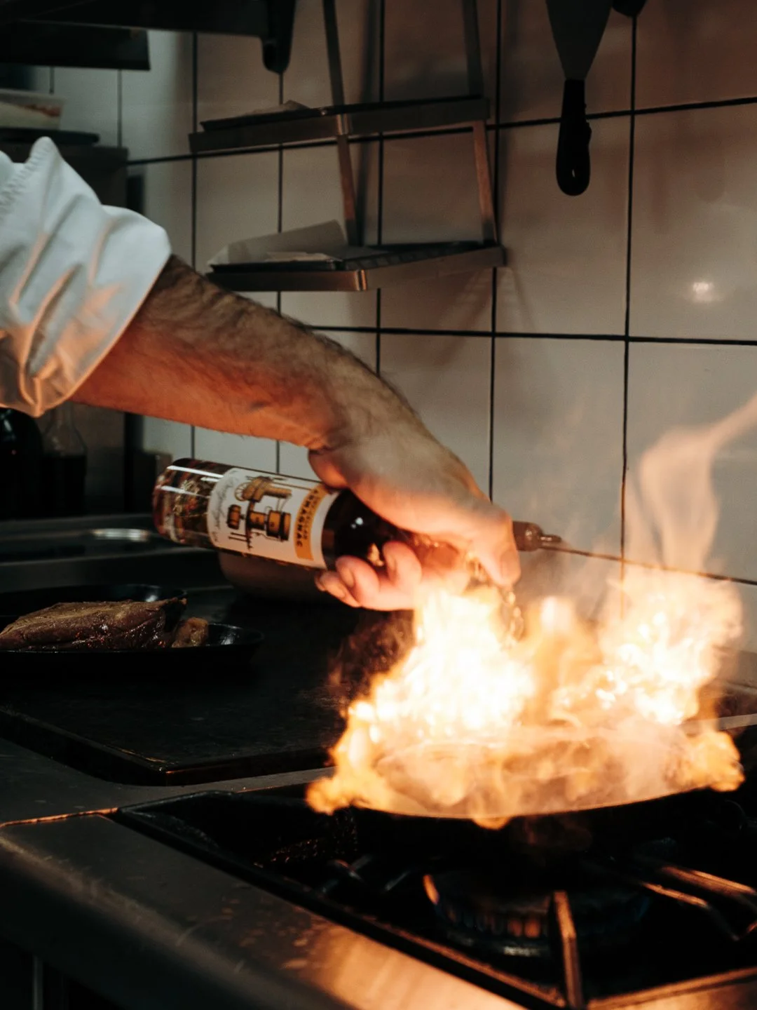 Chef flambant un plat à l'armagnac Dartigalongue en cuisine professionnelle