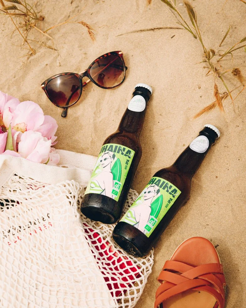 Deux bouteilles Uhaina IPA bio posées dans le sable, lifestyle bière Pays Basque