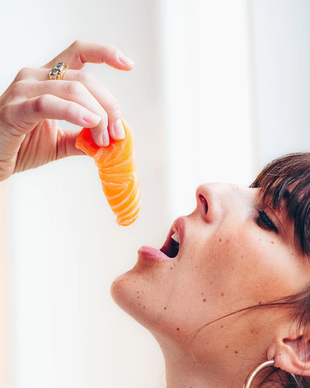 Portrait de profil d'une femme s'apprêtant à manger un nigiri saumon à la main
