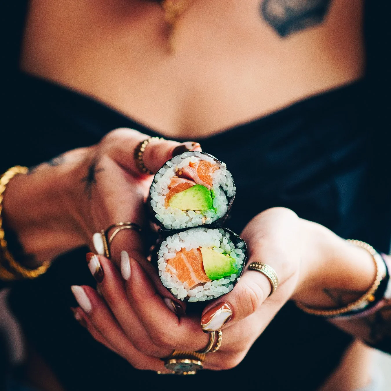 Mains tenant un gros maki coupé en deux montrant le saumon et l'avocat, photographie culinaire Landes