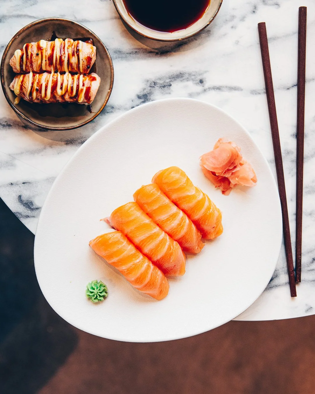 Vue aérienne de plateaux de sushis et makis sur une table mixte marbre et bois