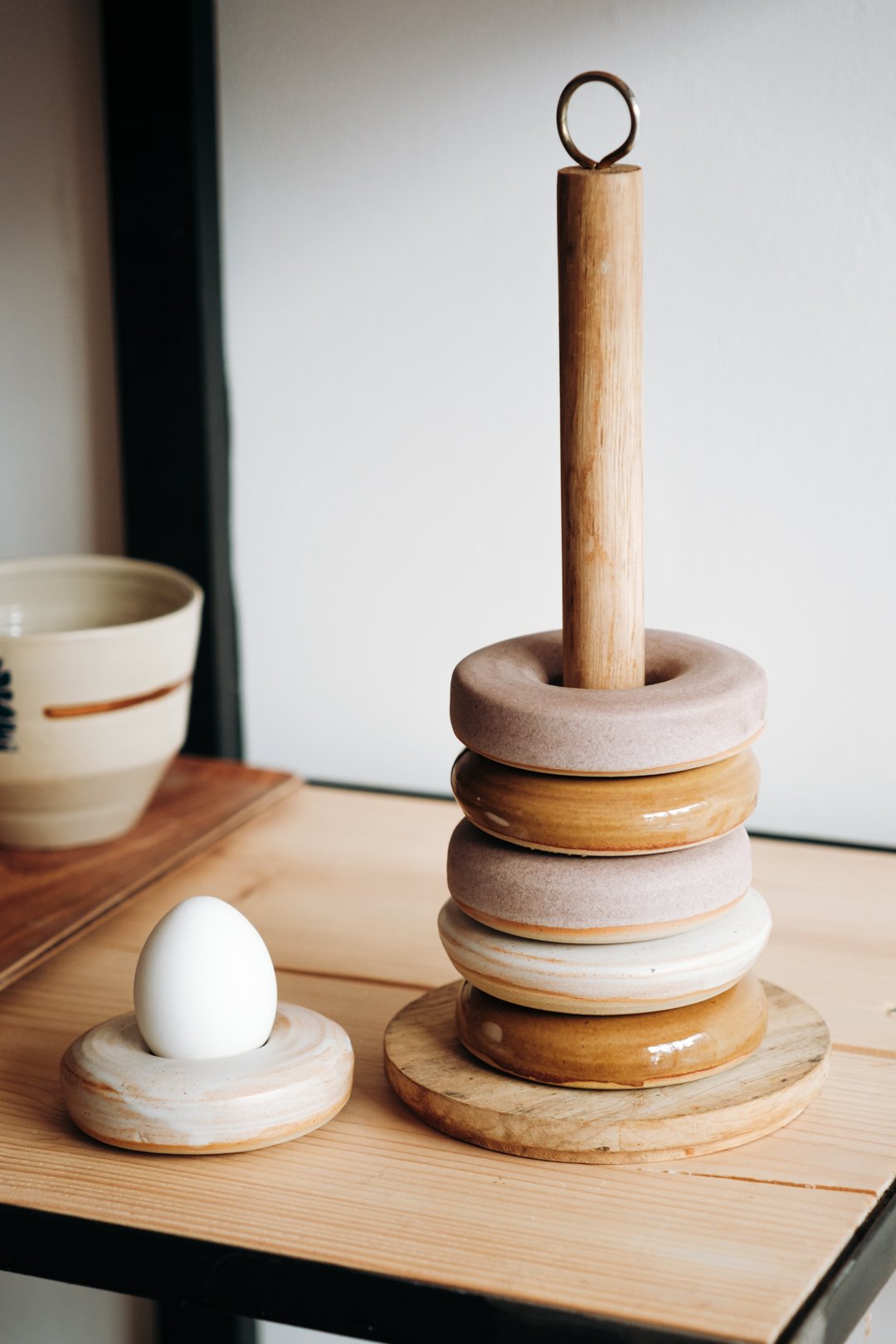 Coquetier en céramique avec un œuf et une pile de coupelles sur une table en bois, reportage photo artisanal dans le 64