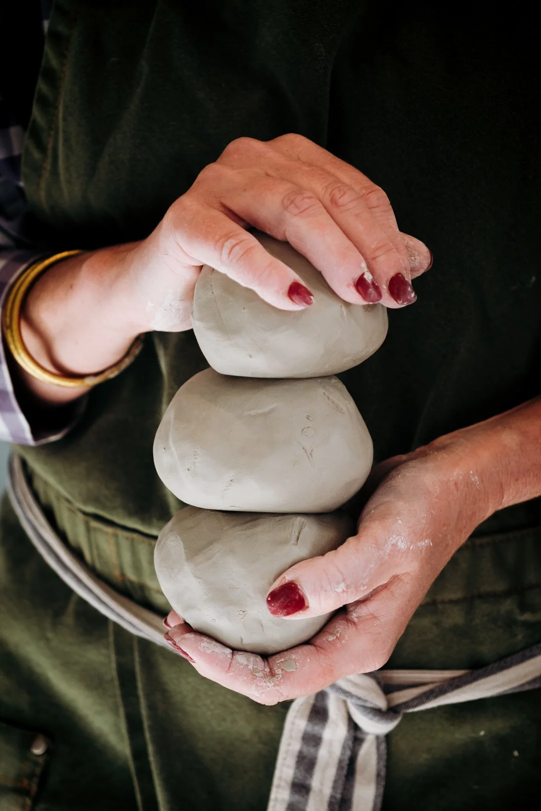 Mains tenant trois boules de terre brute préparées pour le tournage, valorisation des matières premières