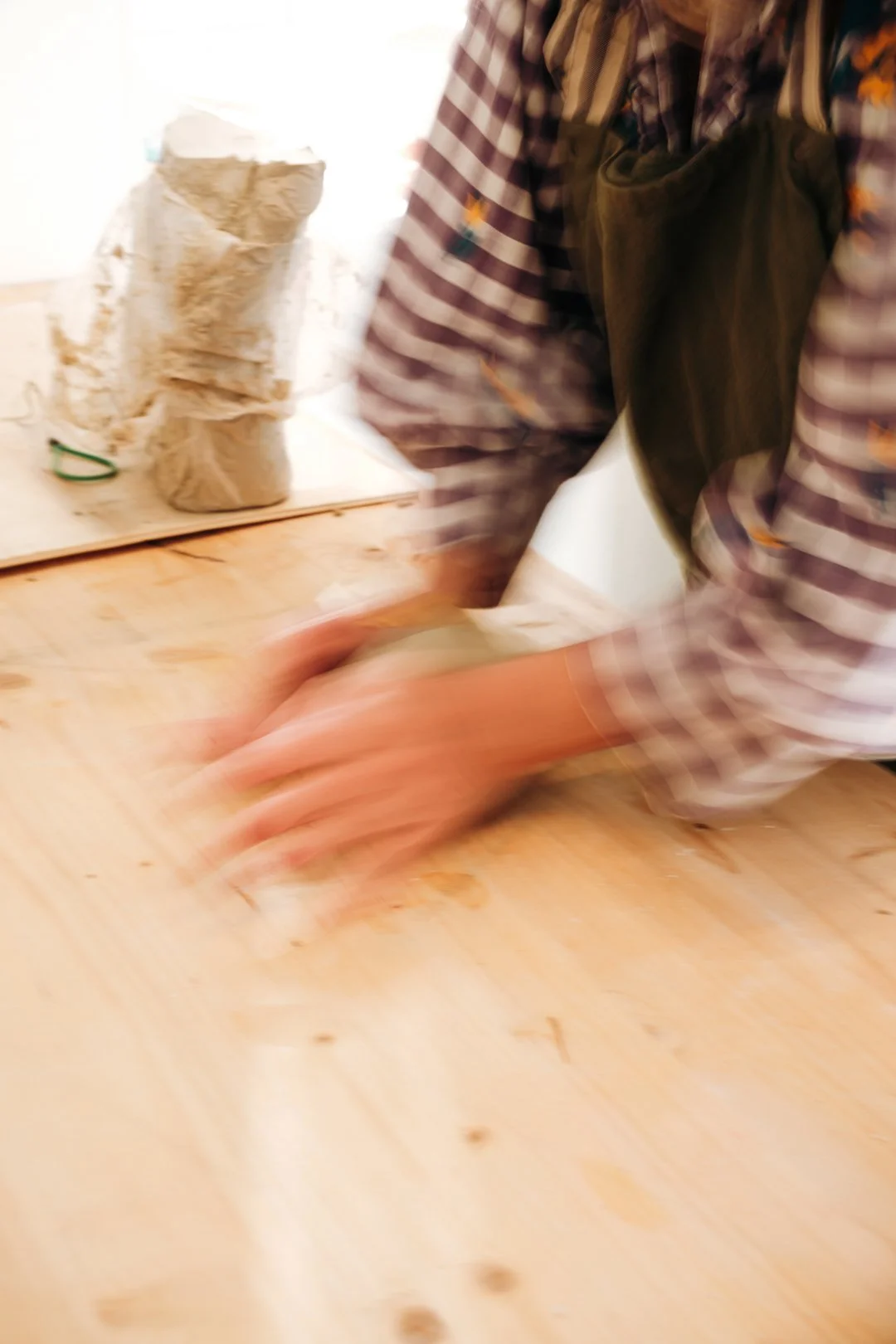 Mains en mouvement malaxant la terre brute dans un atelier de poterie, reportage métier céramiste