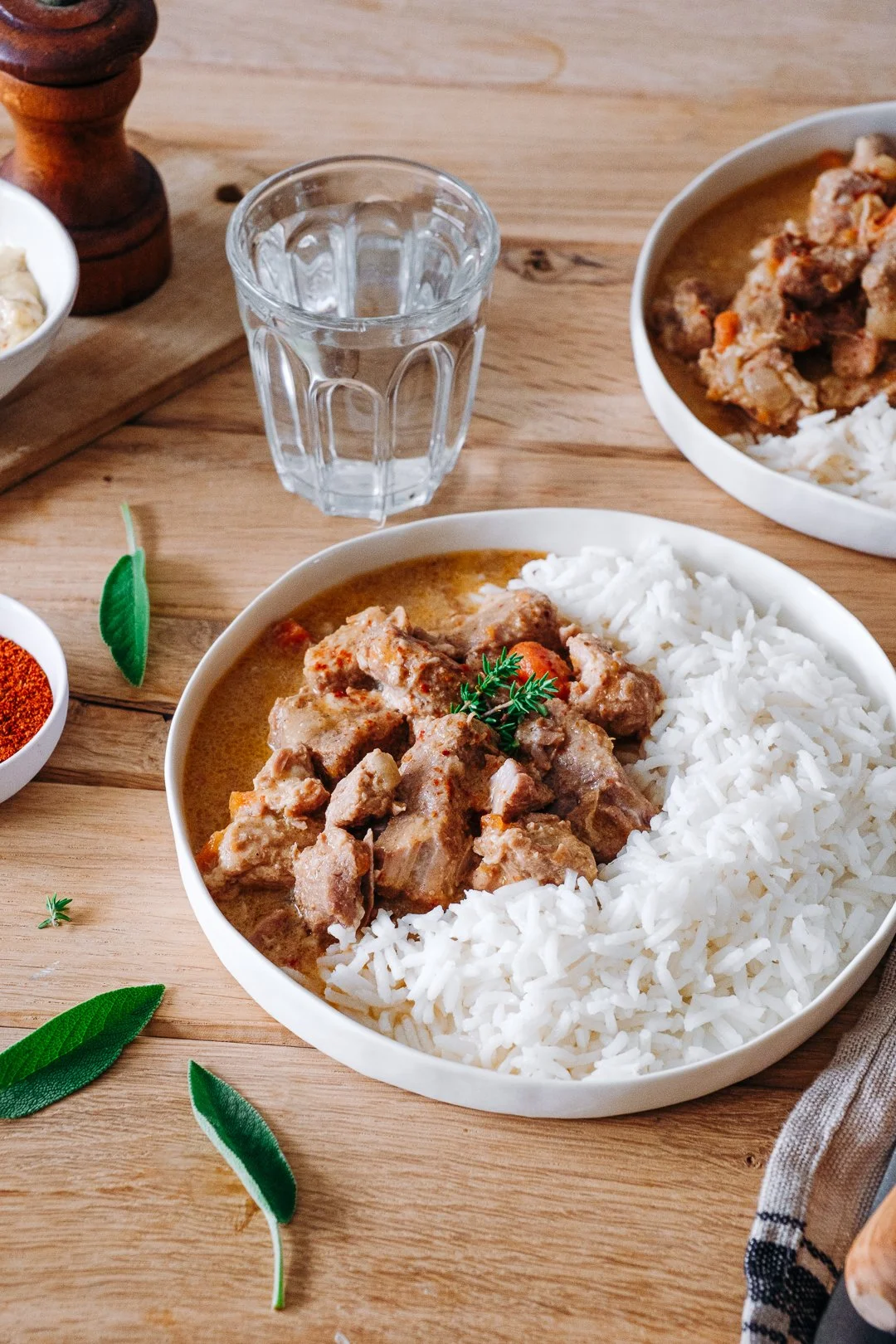 Assiette de porc cuisiné à la moutarde et riz blanc décorée de sauge et piment, photographe culinaire Pays Basque
