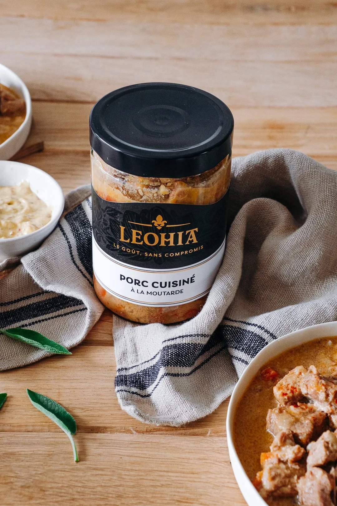 Bocal de Porc cuisiné à la moutarde Leohia sur un torchon à rayures avec bol de moutarde à l'ancienne, photographie de produits food