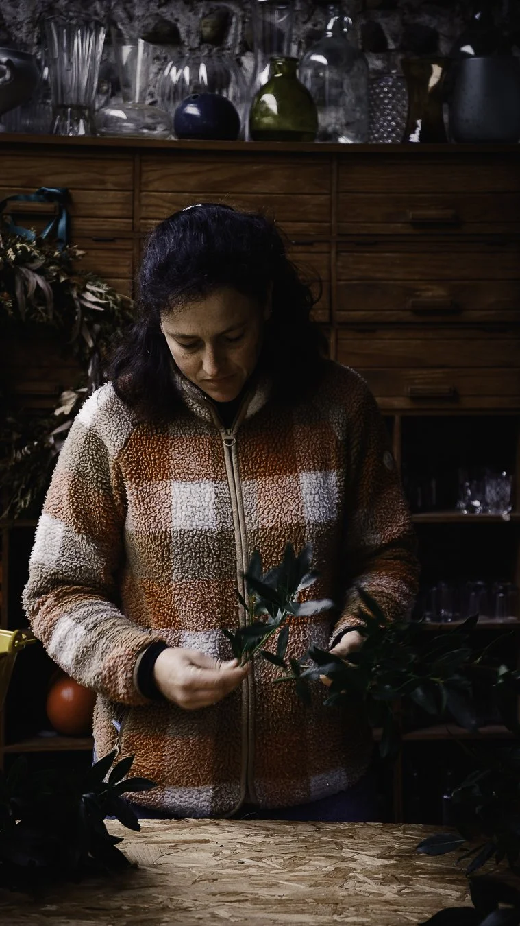 Lauren dans son atelier à Monein, préparant un bouquet avec des feuillages après la récolte matinale