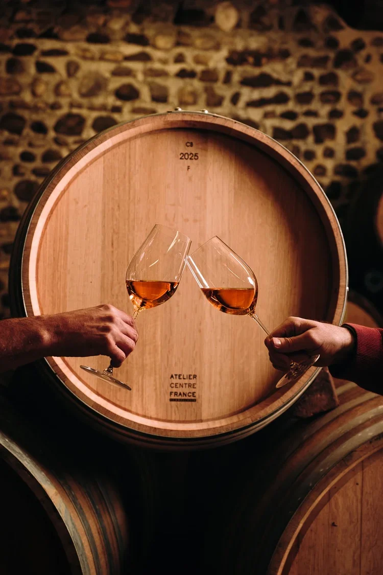 Deux mains portant des verres d'eau-de-vie en cheers sur un tonneau, cave au Pays Basque