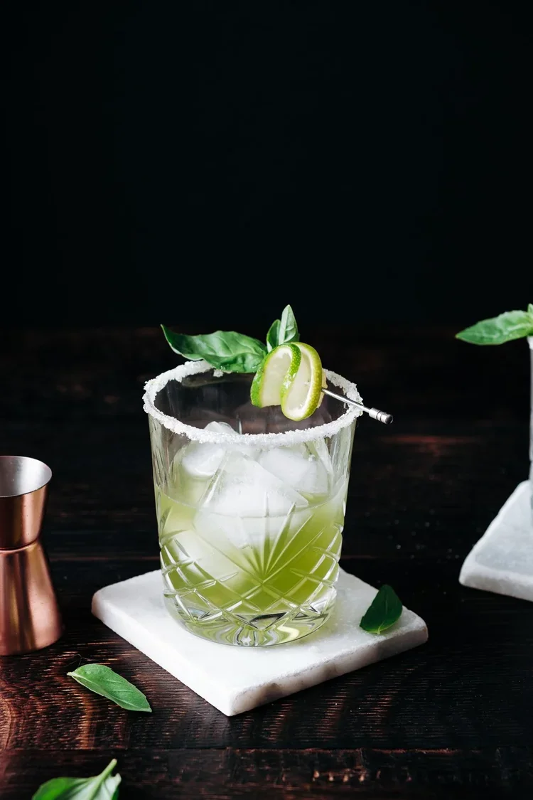 Cocktail à base de spiritueux Brana avec basilic et citron vert, photographie studio fond sombre