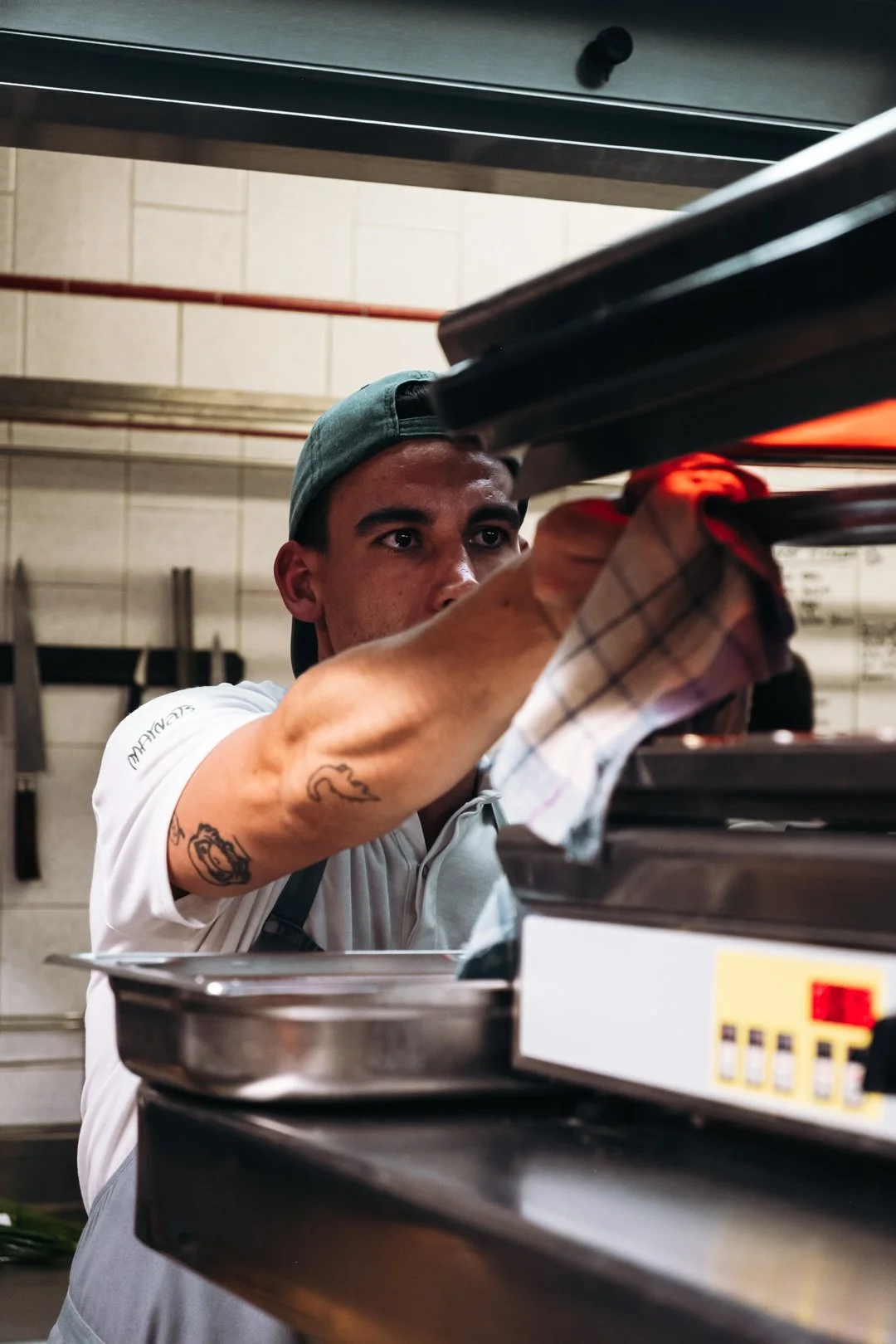 Commis ouvrant un four avec lumiere rouge interieure pendant le service chez Maynats.