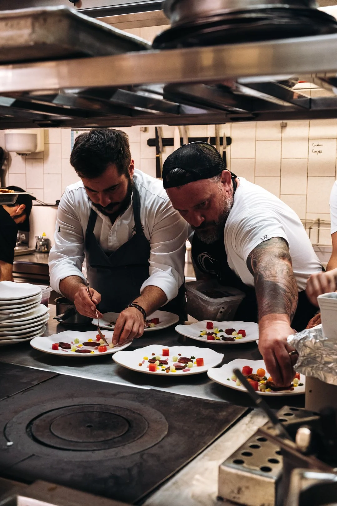 Deux chefs dressant des assiettes gastronomiques en parallele lors du diner a 10 mains.