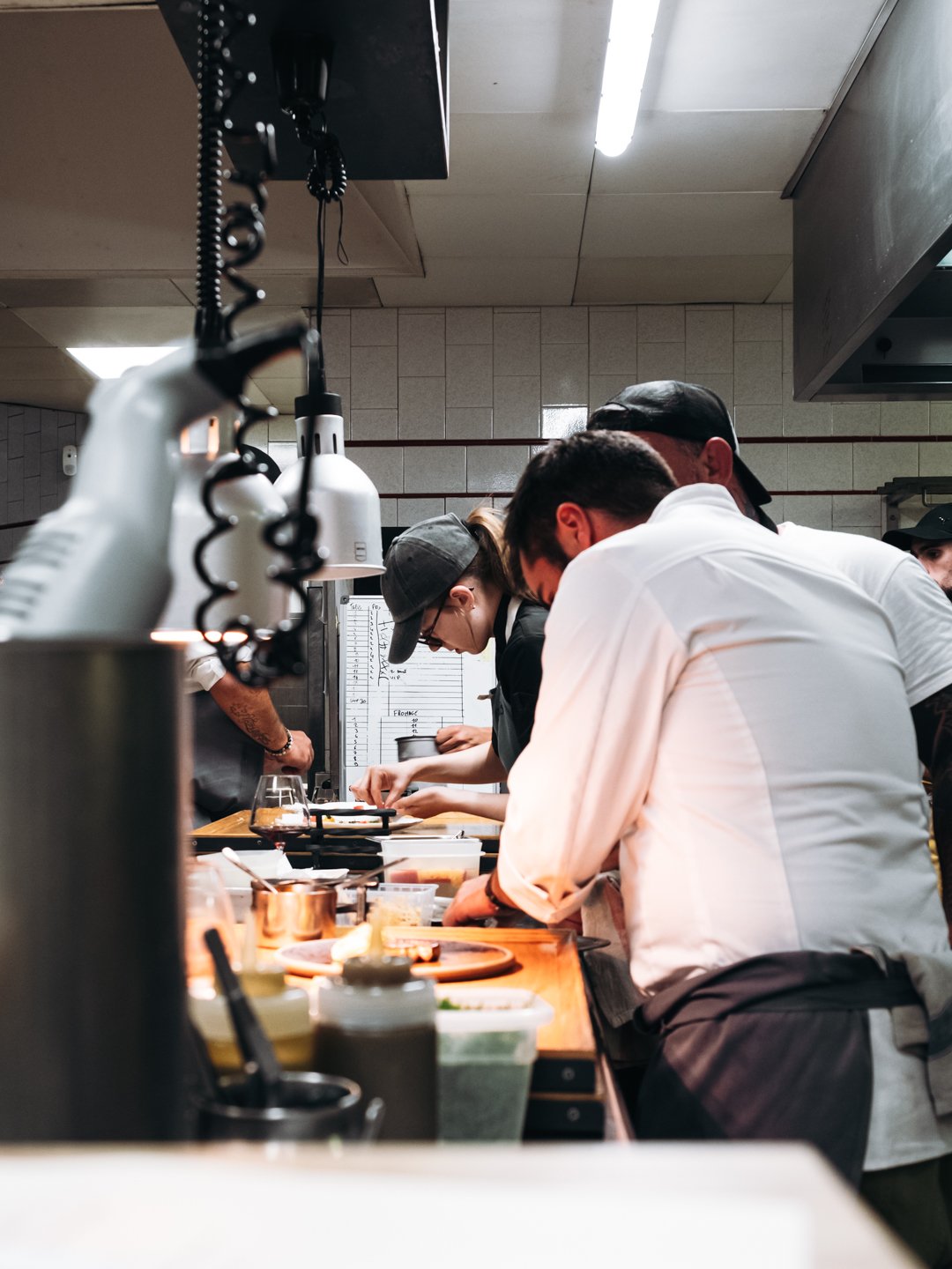 Equipe en cuisine penchee sur le passe lors du service du diner a 10 mains chez Maynats.
