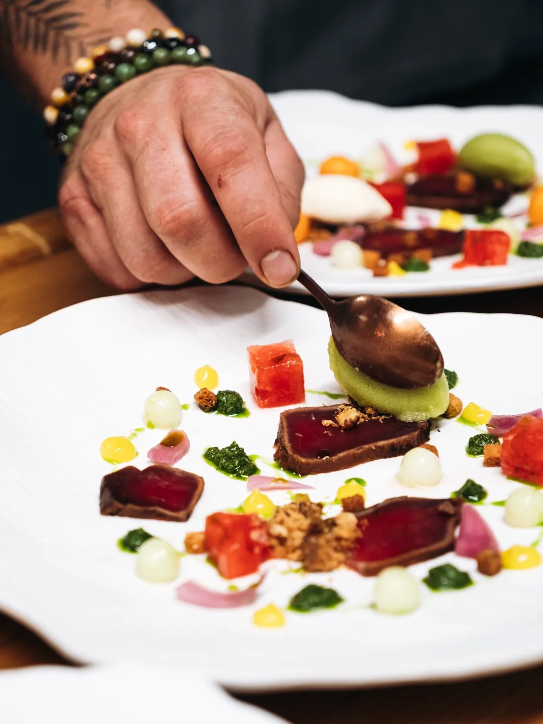 Main posant un element sur une assiette gastronomique coloree, diner a 10 mains a Pau.