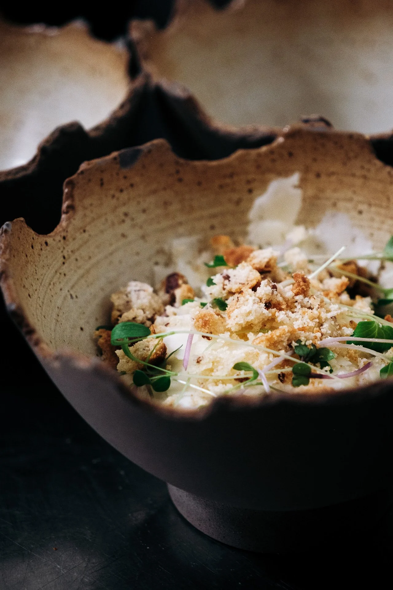 Bol en ceramique brute avec preparation blanche, crumble et herbes fraiches, diner 7 chefs Snug.