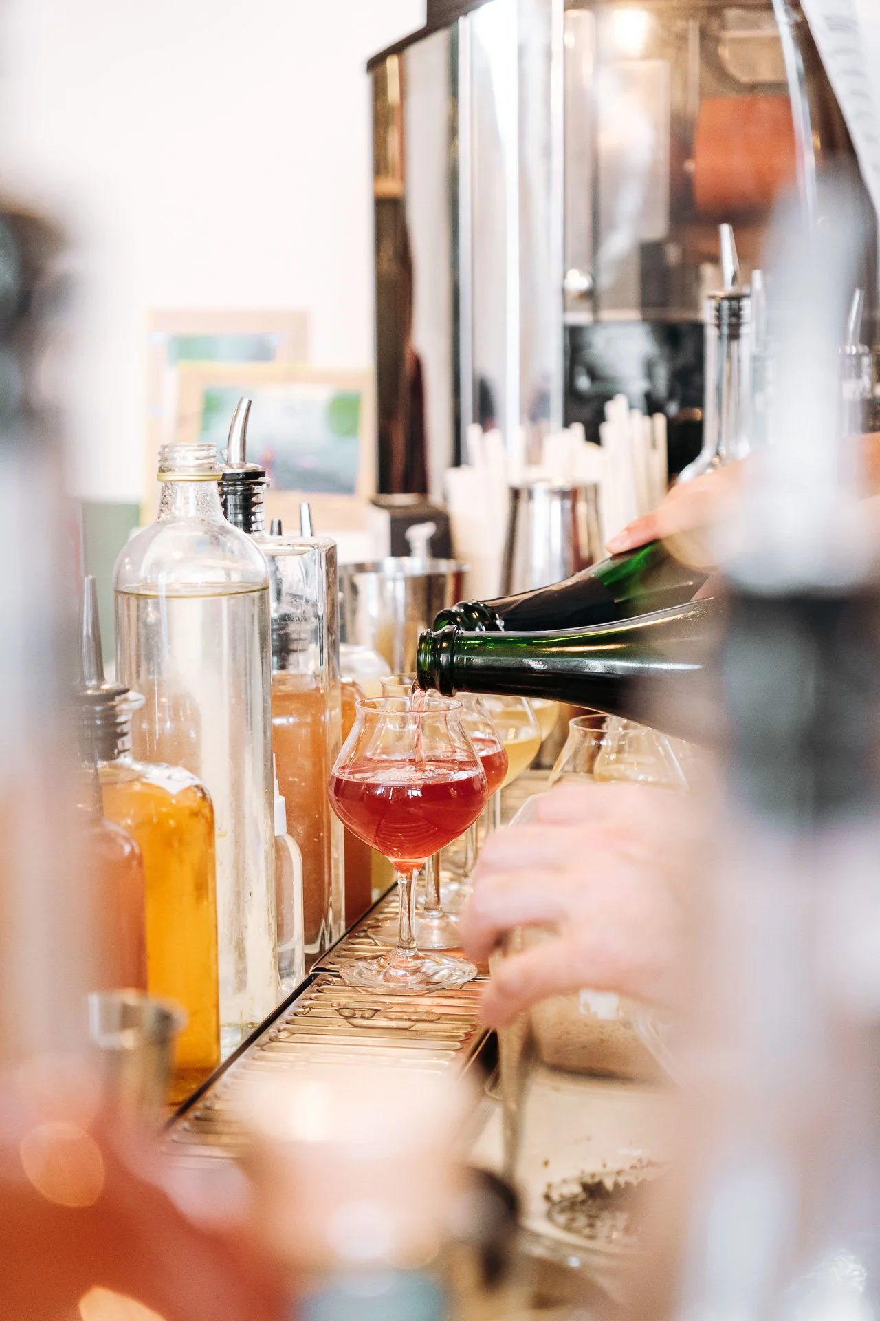 Bouteille versee dans un verre de cocktail rouge au bar du Snug, accord mets et cocktails.