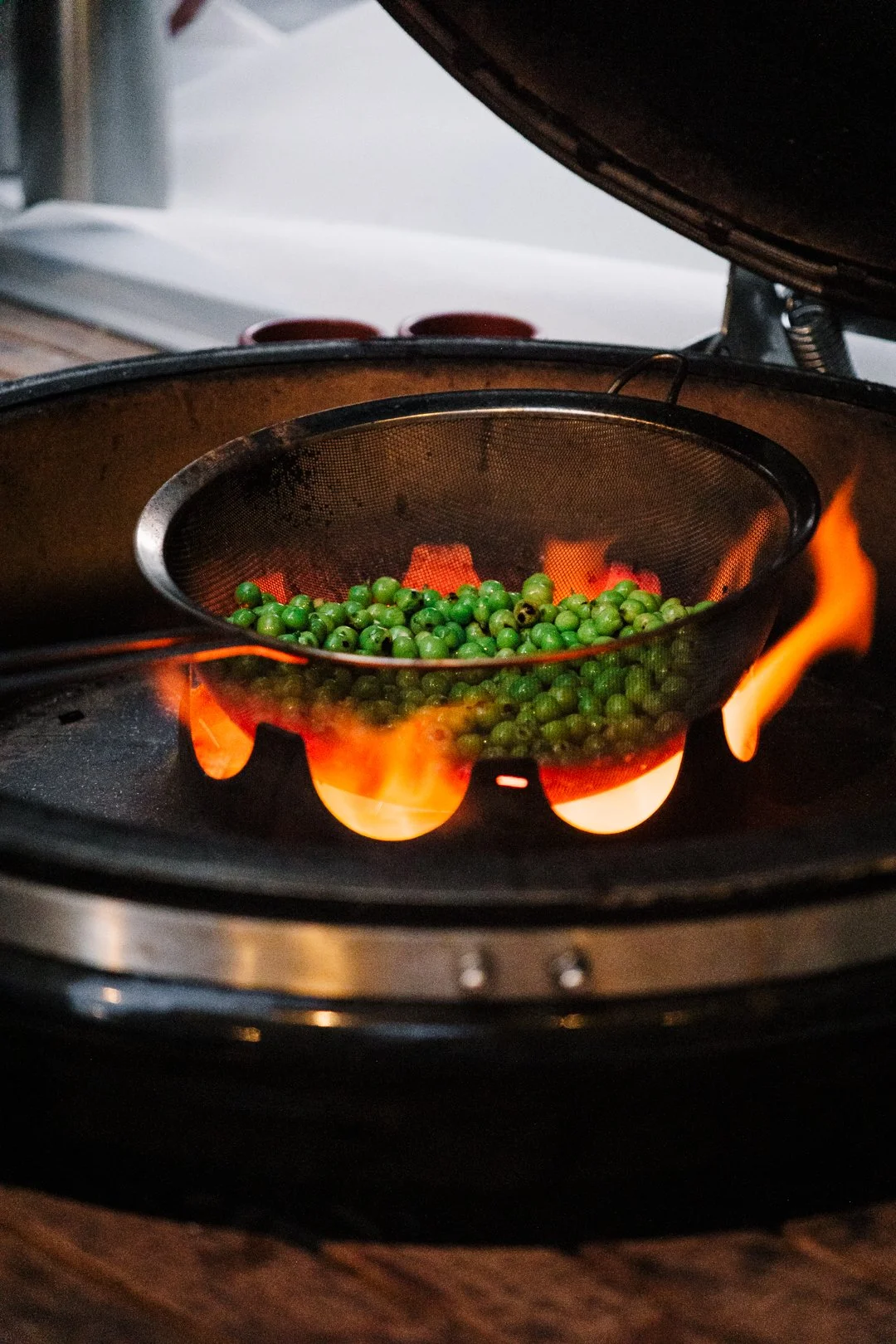 Petits pois dans une passoire sur les braises d'un kamado lors du Tapas Pyrenees Club a Pau.