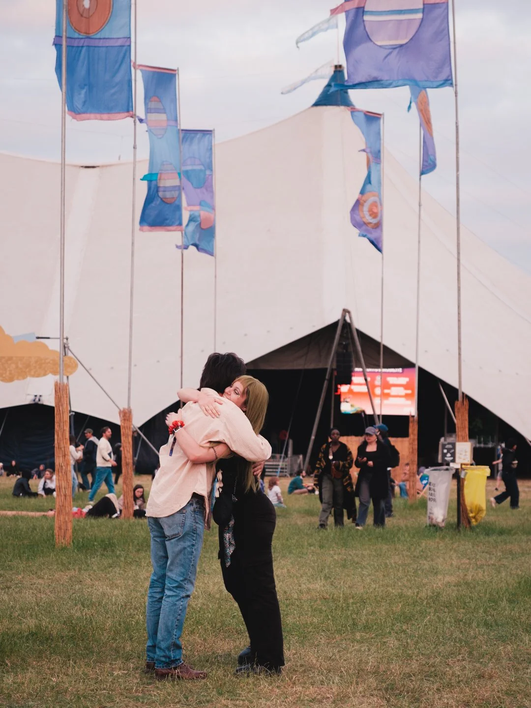 Couple s'enlaçant devant une scene sous tente avec drapeaux colores, We Love Green 2026