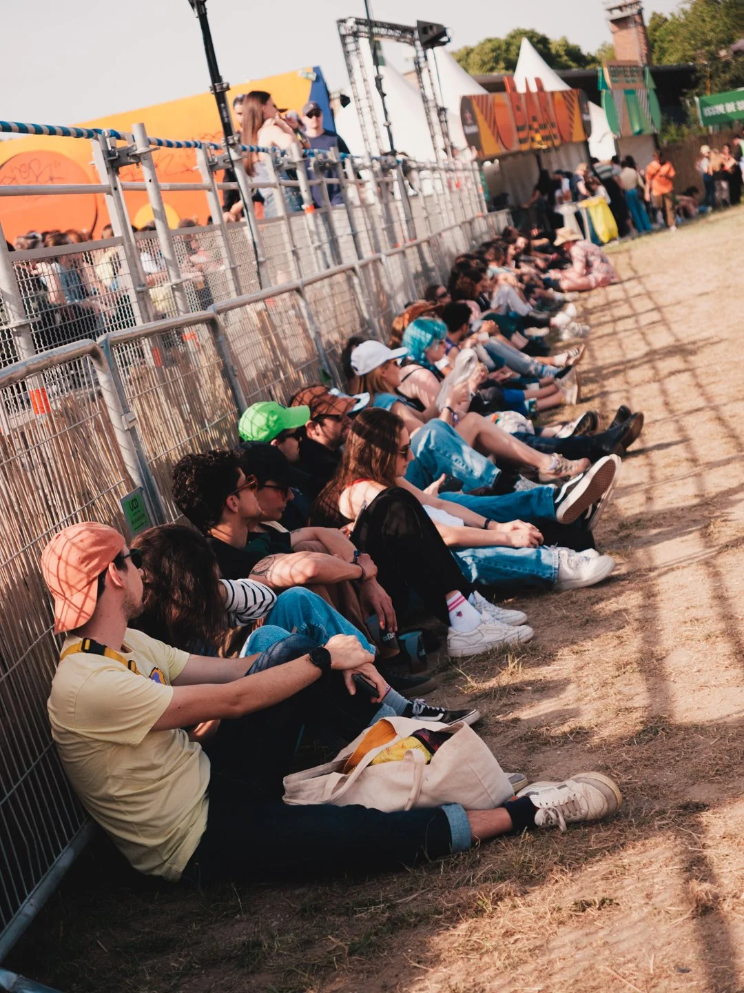 Rangee de festivaliers assis contre une barriere au soleil, We Love Green Bois de Vincennes
