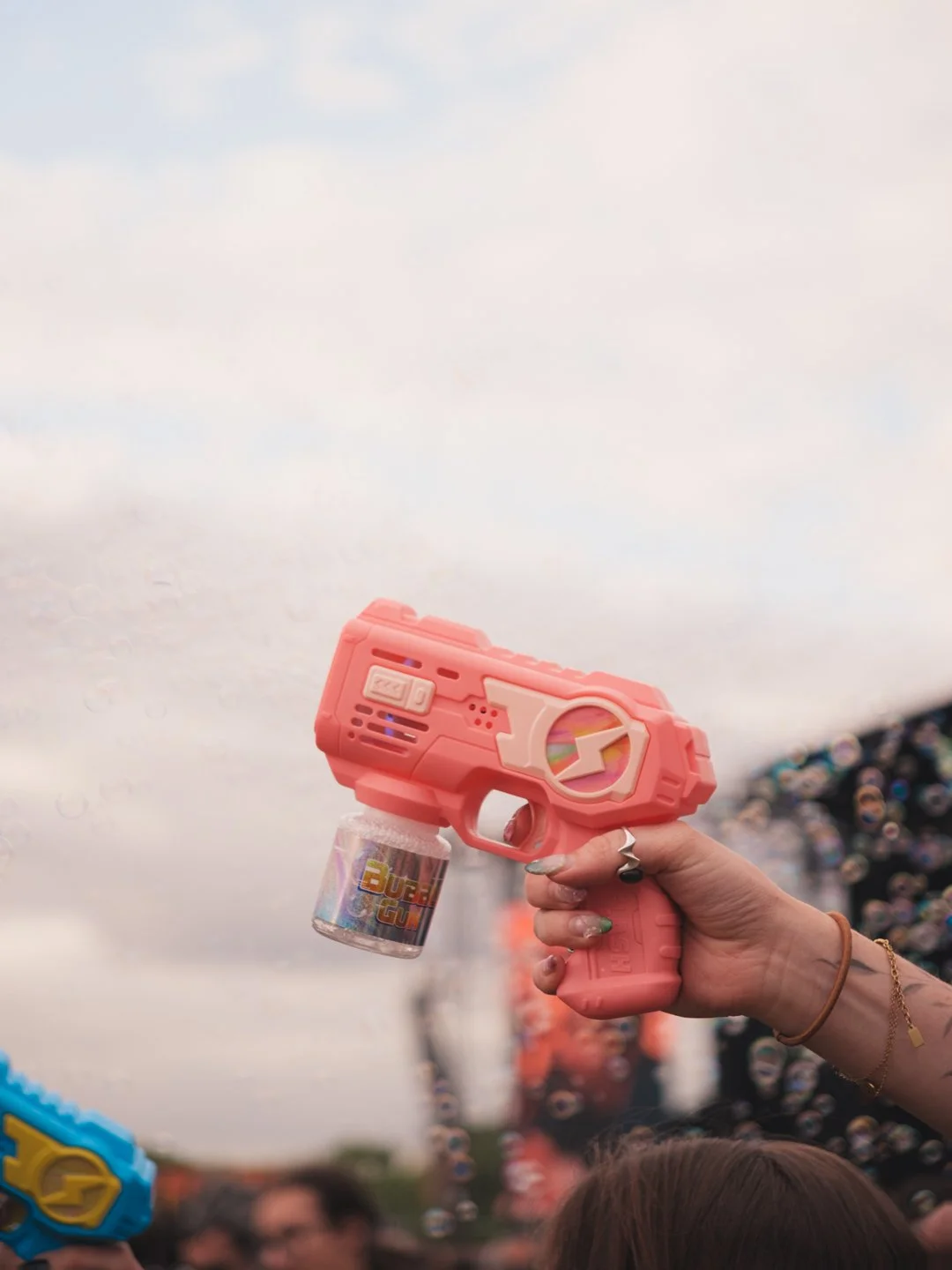 Main tenant un pistolet a bulles rose dans la foule du festival We Love Green a Paris.