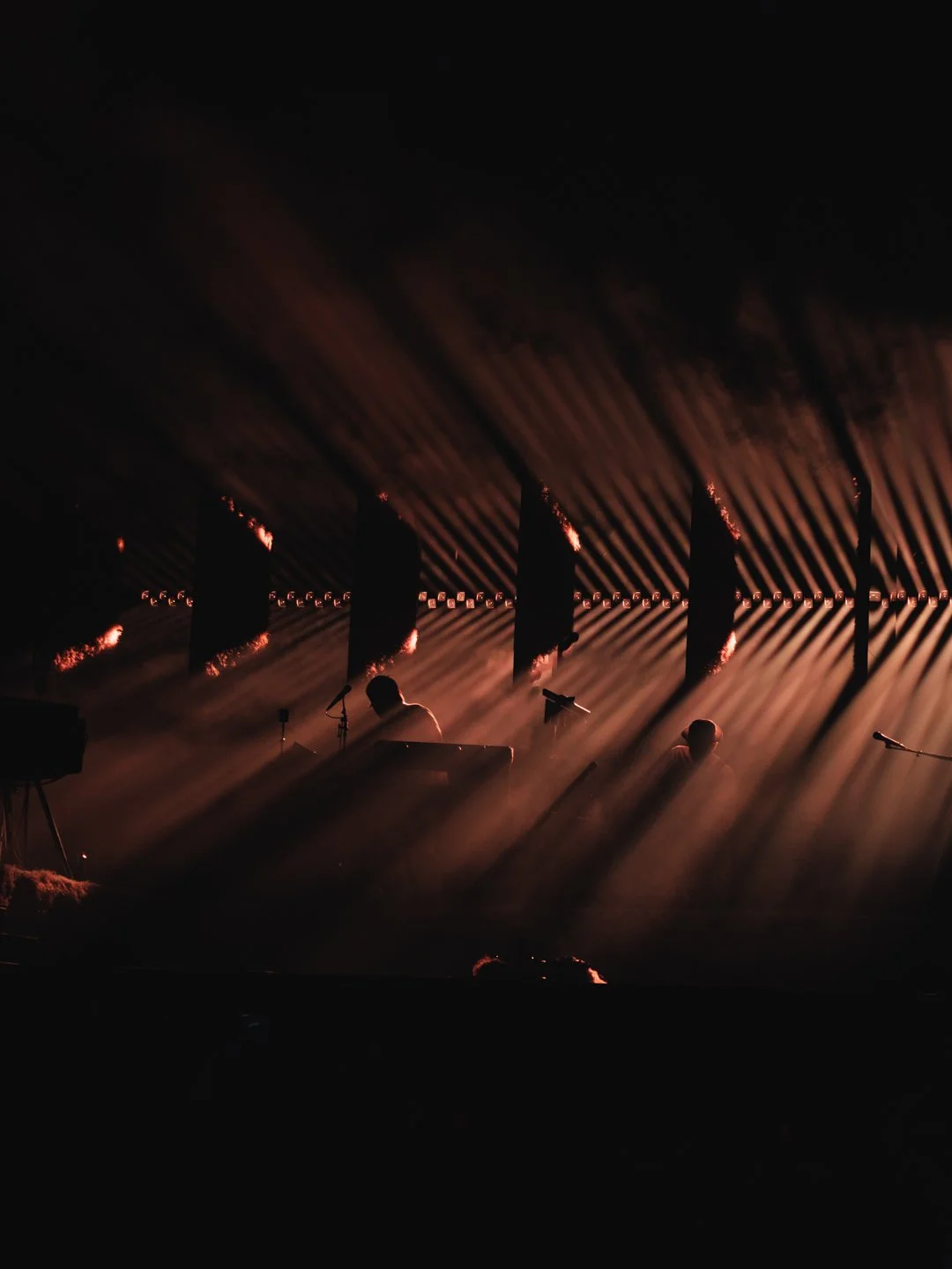 Rayons lumineux cuivres en eventail sur scene sombre avec musiciens en silhouette, We Love Green