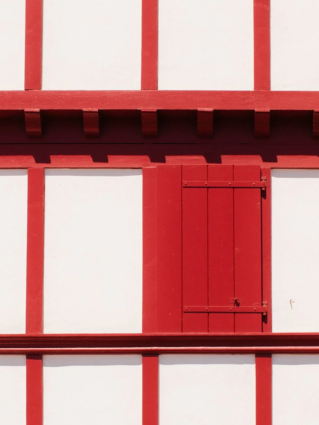 Détail graphique et minimaliste d'une façade traditionnelle basque rouge et blanche