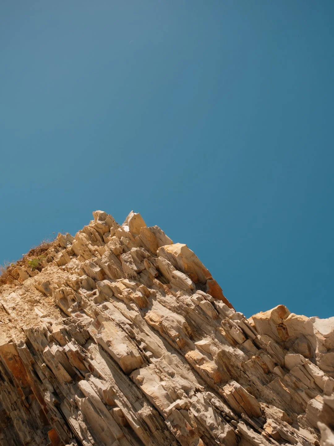 Sommet d'une falaise rocheuse très graphique se découpant sur un ciel bleu sans nuage