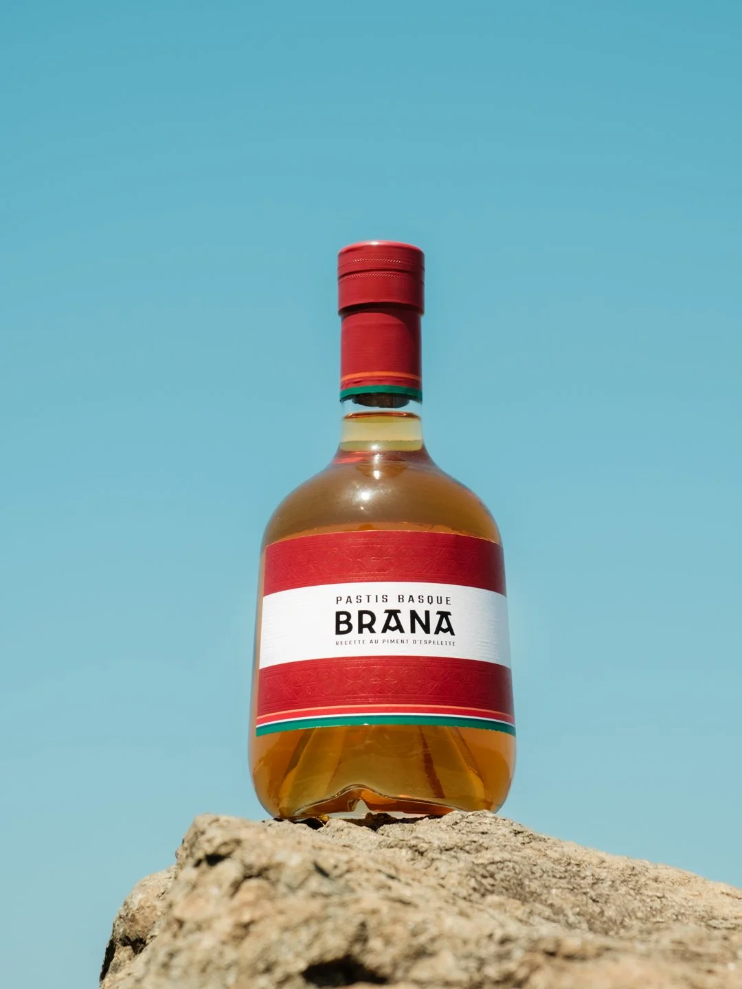 Bouteille du nouveau Pastis Basque Brana photographiée en contre-plongée sur un rocher.
