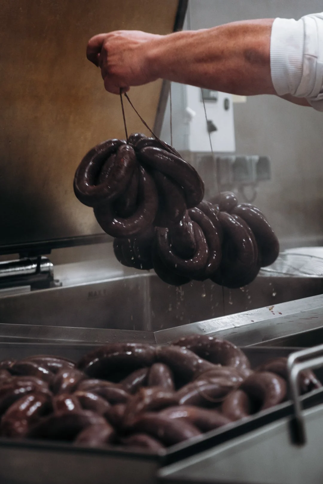 Sortie des grappes de boudin noir au-dessus des cuves dans l'atelier de production des Accords d'Aurema
