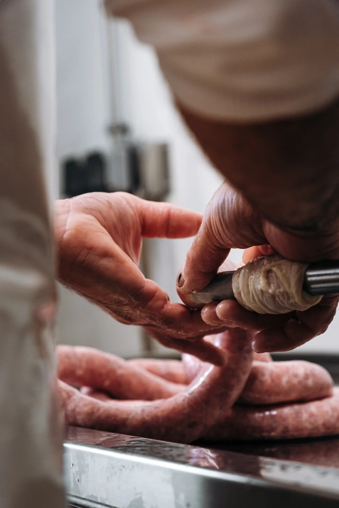 Gros plan sur les mains de l'artisan charcutier pendant l'embossage manuel des saucisses