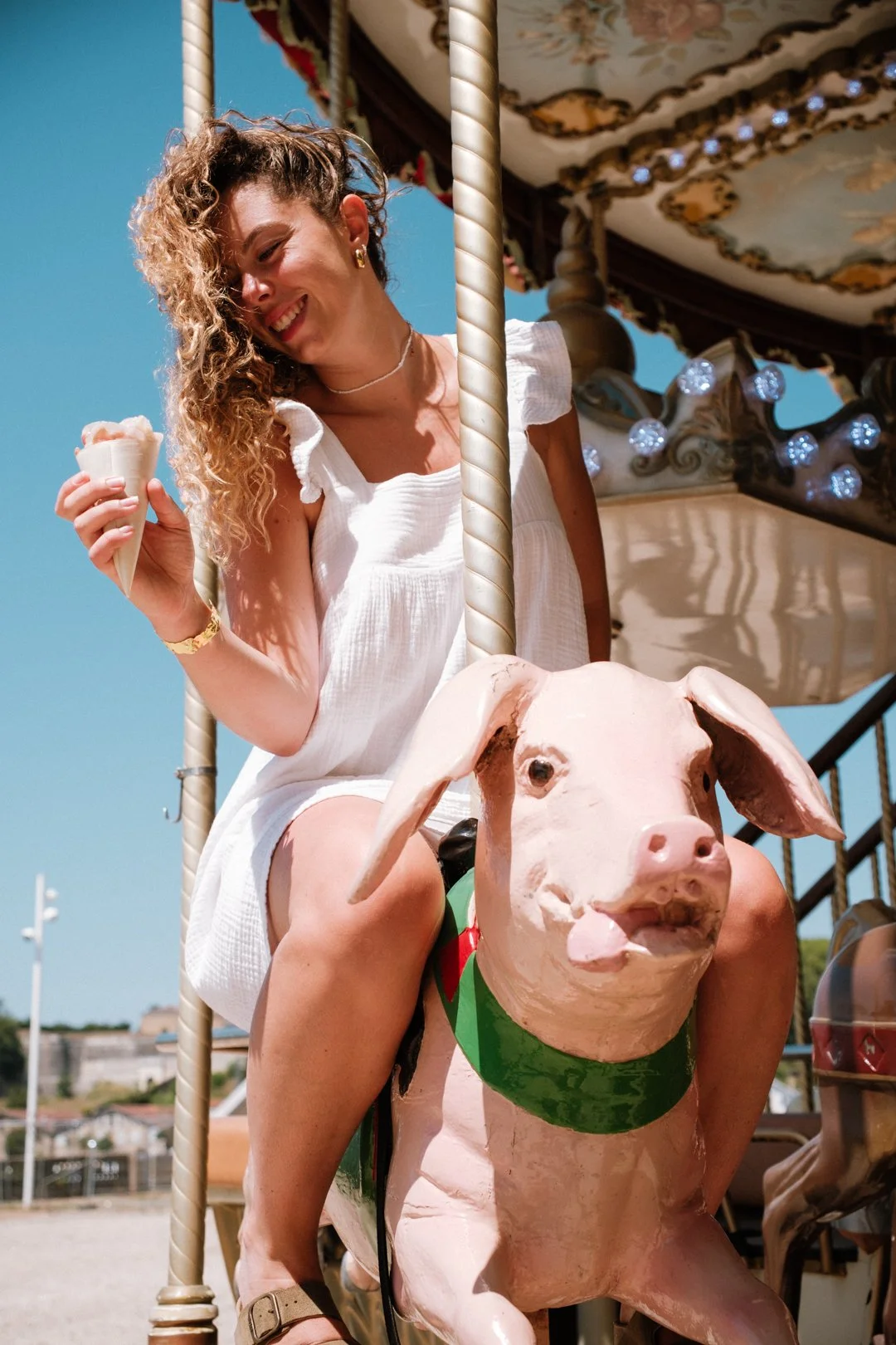 Femme riant sur le sujet d'un manège en forme de cochon avec son cornet à la main à Bayonne