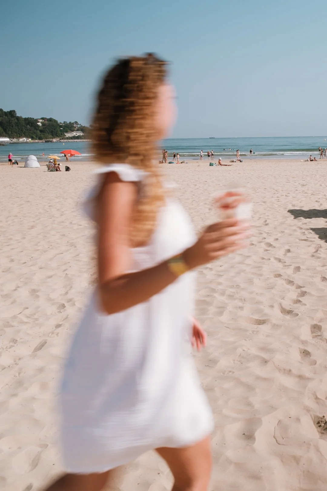 Silhouette floue d'une femme en robe blanche courant sur la plage avec un cornet à Hendaye