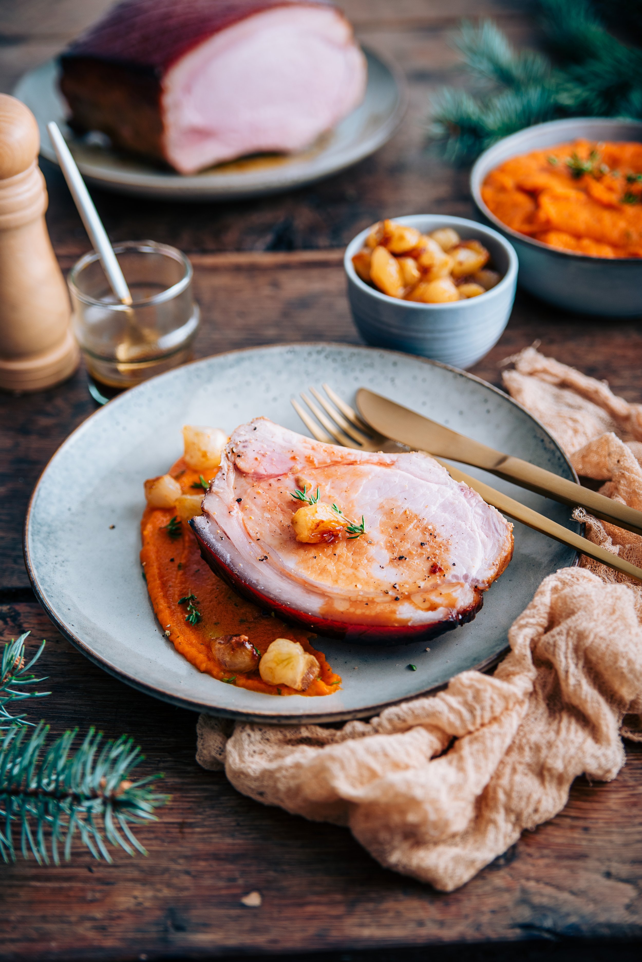 Tranche de carré de porc rôti servie sur de la purée de patate douce avec des petits oignons rôtis