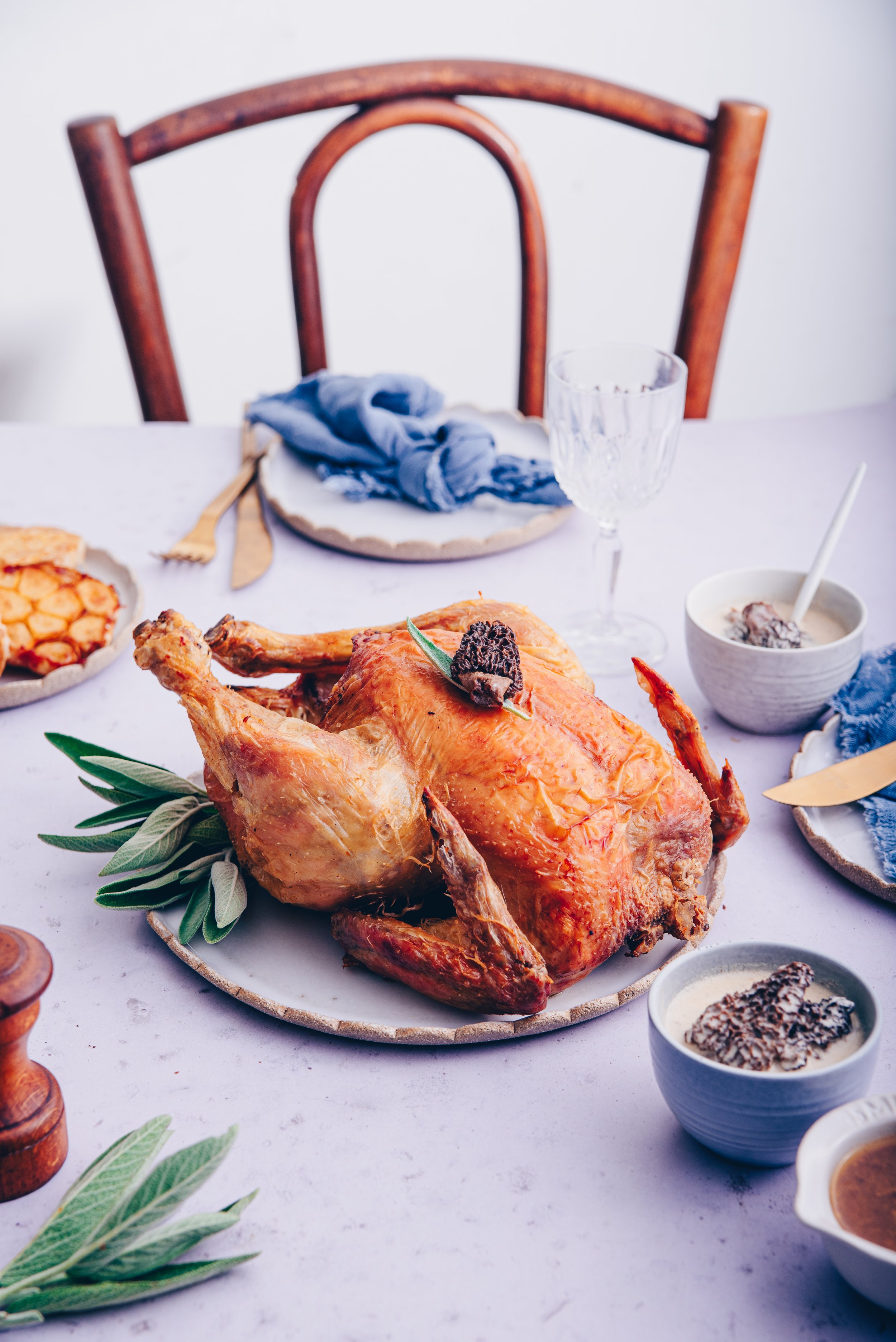 Poulet entier rôti doré servi sur plat en céramique avec sa sauce aux morilles.