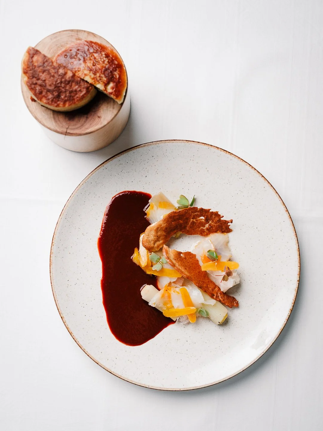 Assiette avec poisson, sauce bordeaux et pain sur support bois, l'Esberit.