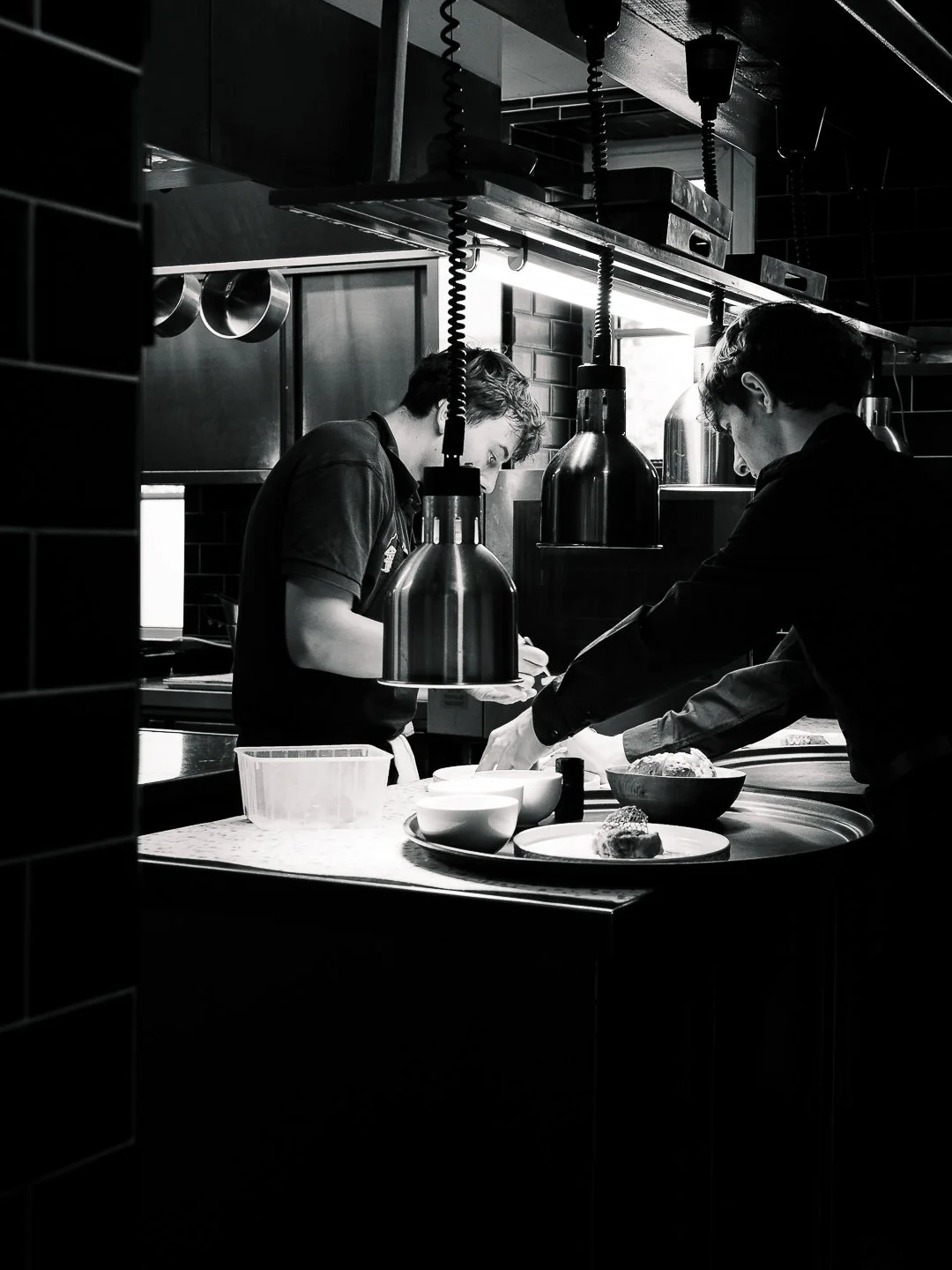 Vue noir et blanc de la cuisine en service avec deux cuisiniers au passe, l'Esberit a Pau.