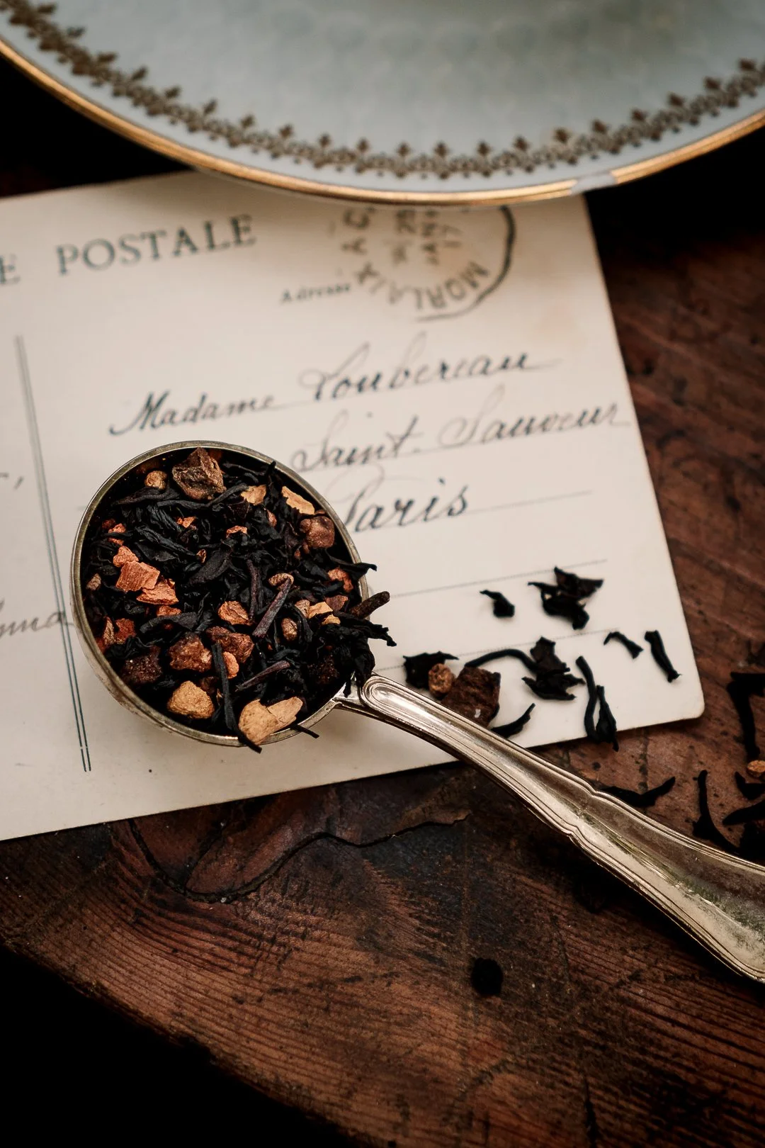 Cuillère de thé noir épicé sur une carte postale ancienne, photo culinaire d’automneCarte postale ancienne, cuillère de thé et feuilles de chêne sur table en bois