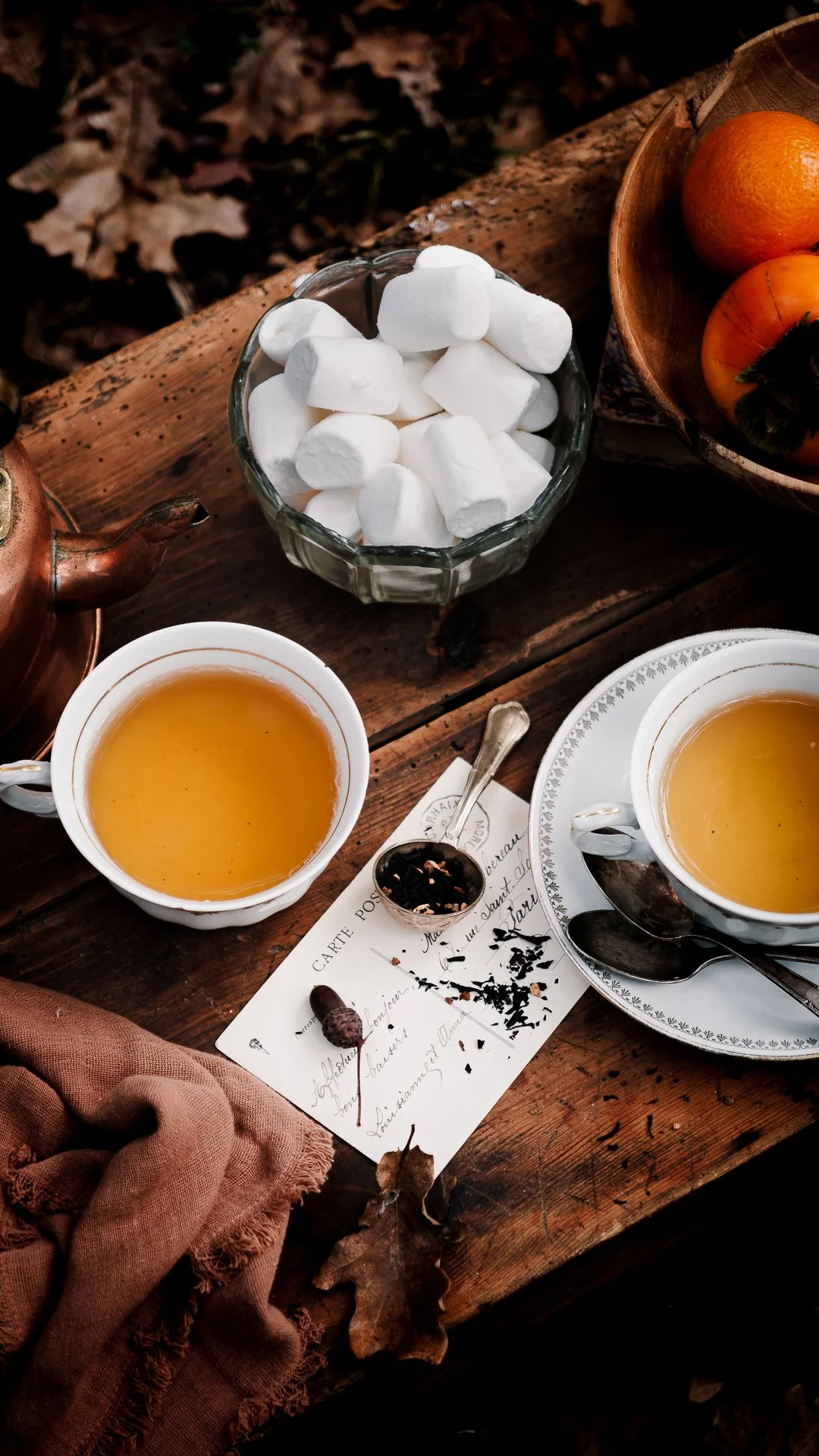Deux tasses de thé, guimauves et kakis sur une table en bois, format stories