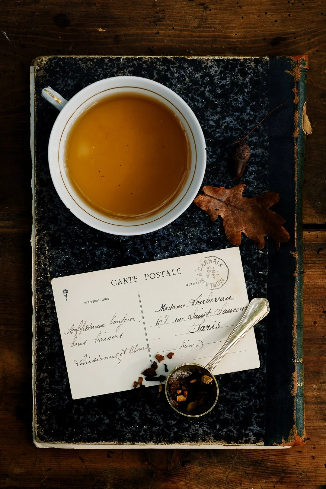 Tasse de thé sur un livre ancien avec carte postale et feuille de chêne