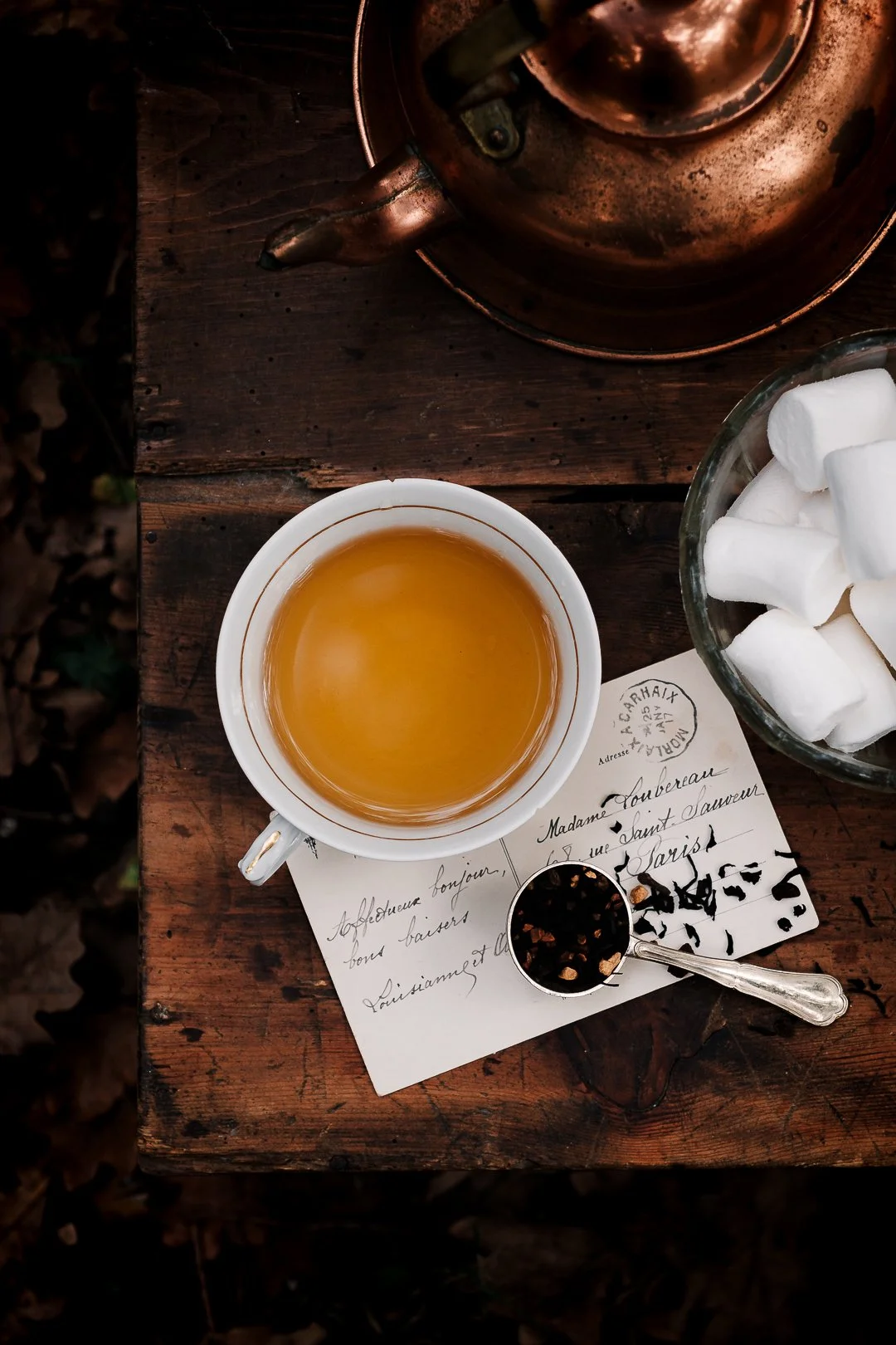 Tasse de thé vue du dessus avec bouilloire en cuivre et guimauves sur table en bois