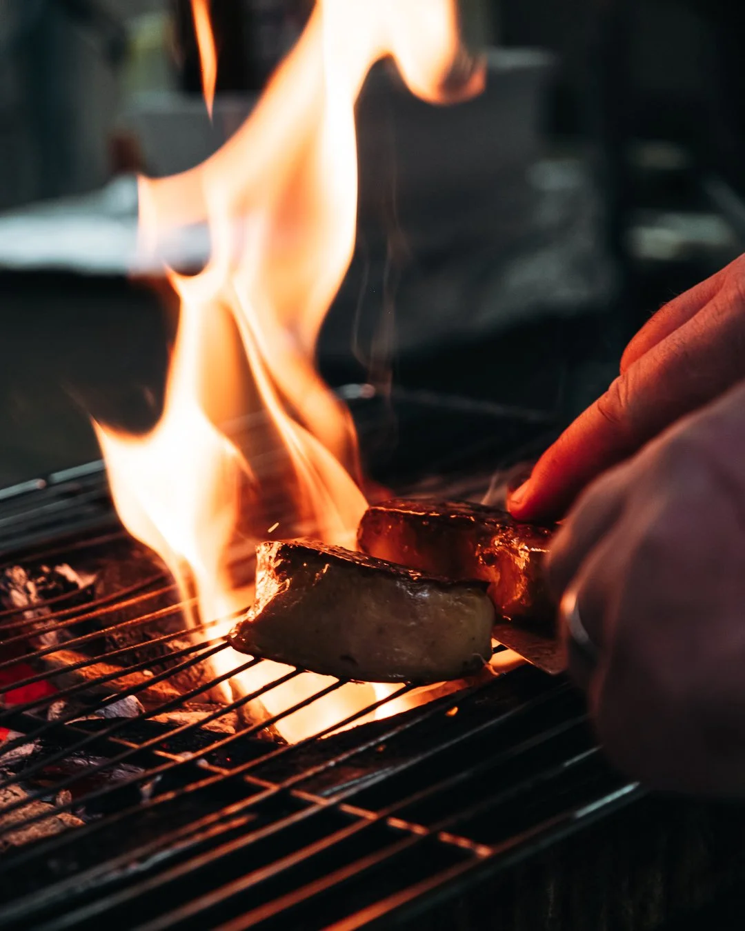 Deux morceaux de viande en train de cuire sur un barbecue avec des flammes