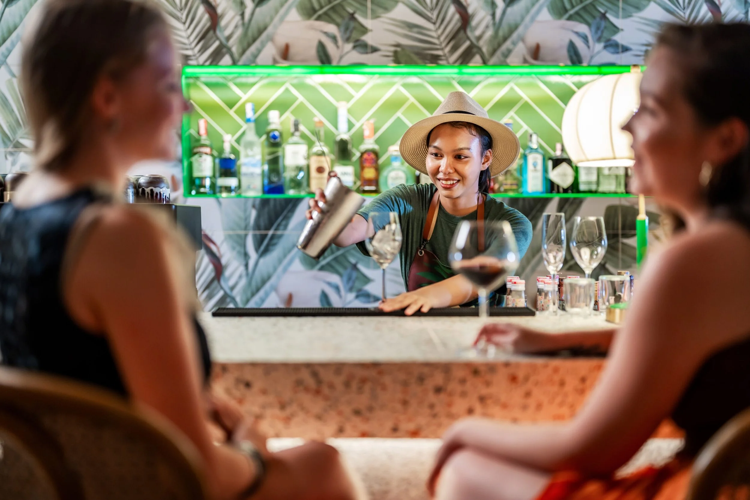A bartender skillfully pouring handcrafted cocktails at Koa Dining, Tolani Koh Samui, a beachfront vegan restaurant.