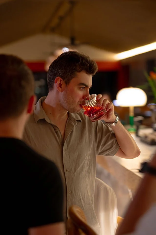A handsome man sipping a classic Negroni cocktail at the bar of Koa Dining, Tolani Koh Samui, enjoying the elegant ambiance.